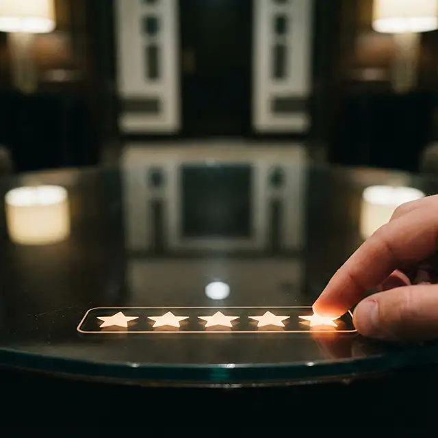 Hand touching the fifth star in a glowing five-star rating on a dark reflective surface.